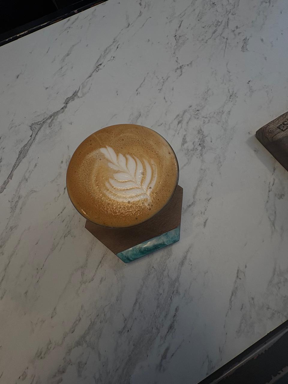 Latte servido sobre un portavasos geométrico