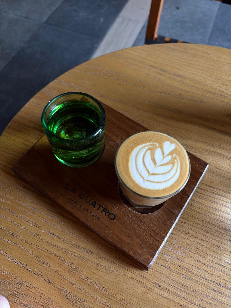 Café y vaso verde servidos en una tabla de madera